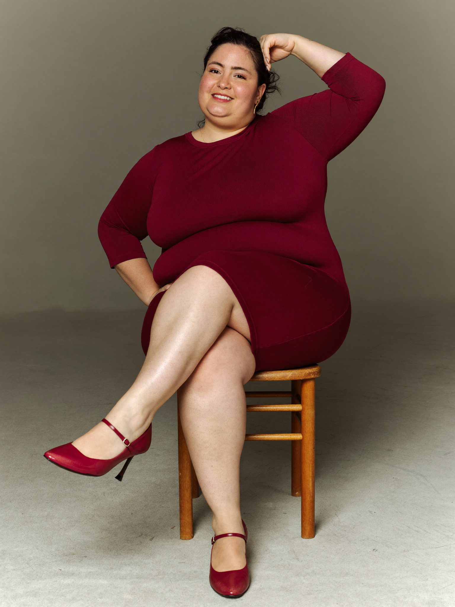 Девушка plus size сидит на краю стула с прямой спиной
